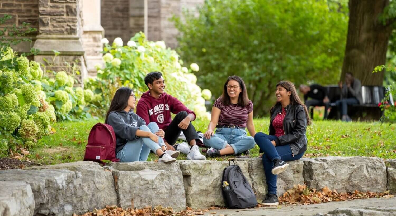 International students sitting on ground or along rocks or benches near and around University Hall.