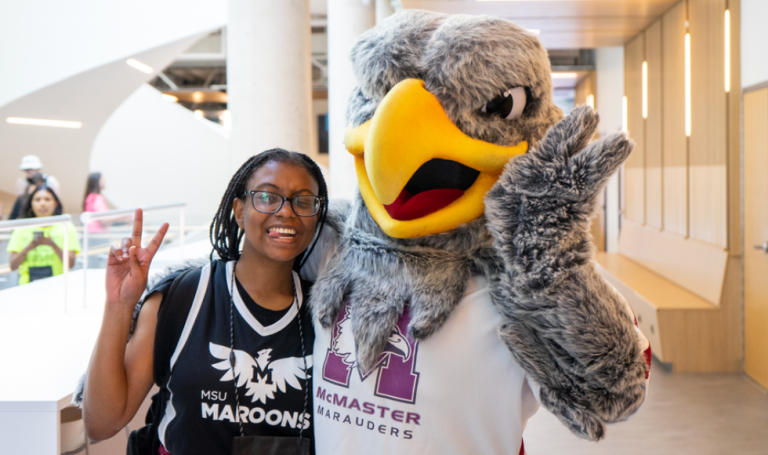 Student and McMaster Marauder mascot giving 