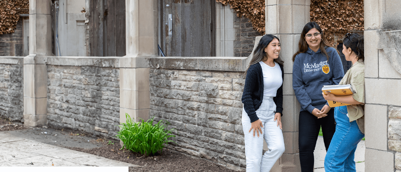 Three students standing and talking by the Edwards Arch on campus.