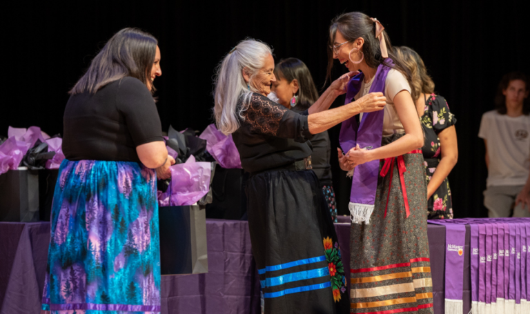 Indigenous staff and Elder congratulating graduating student