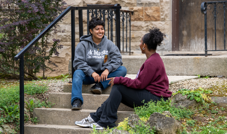 Two students sitting on stairs talking.