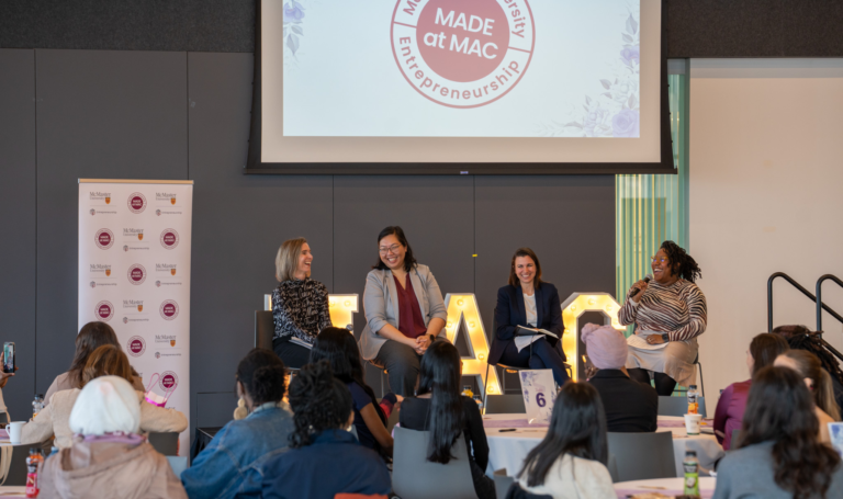 Four panelists laughing on stage at entrepreneurship event.