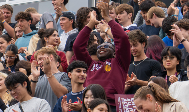 Crowd of excited students in stadium seats.