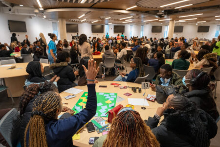 Room full of students, some with their hands up, during event