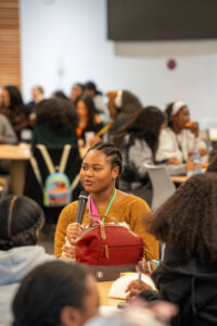 Student holding mic during event with full room of peers